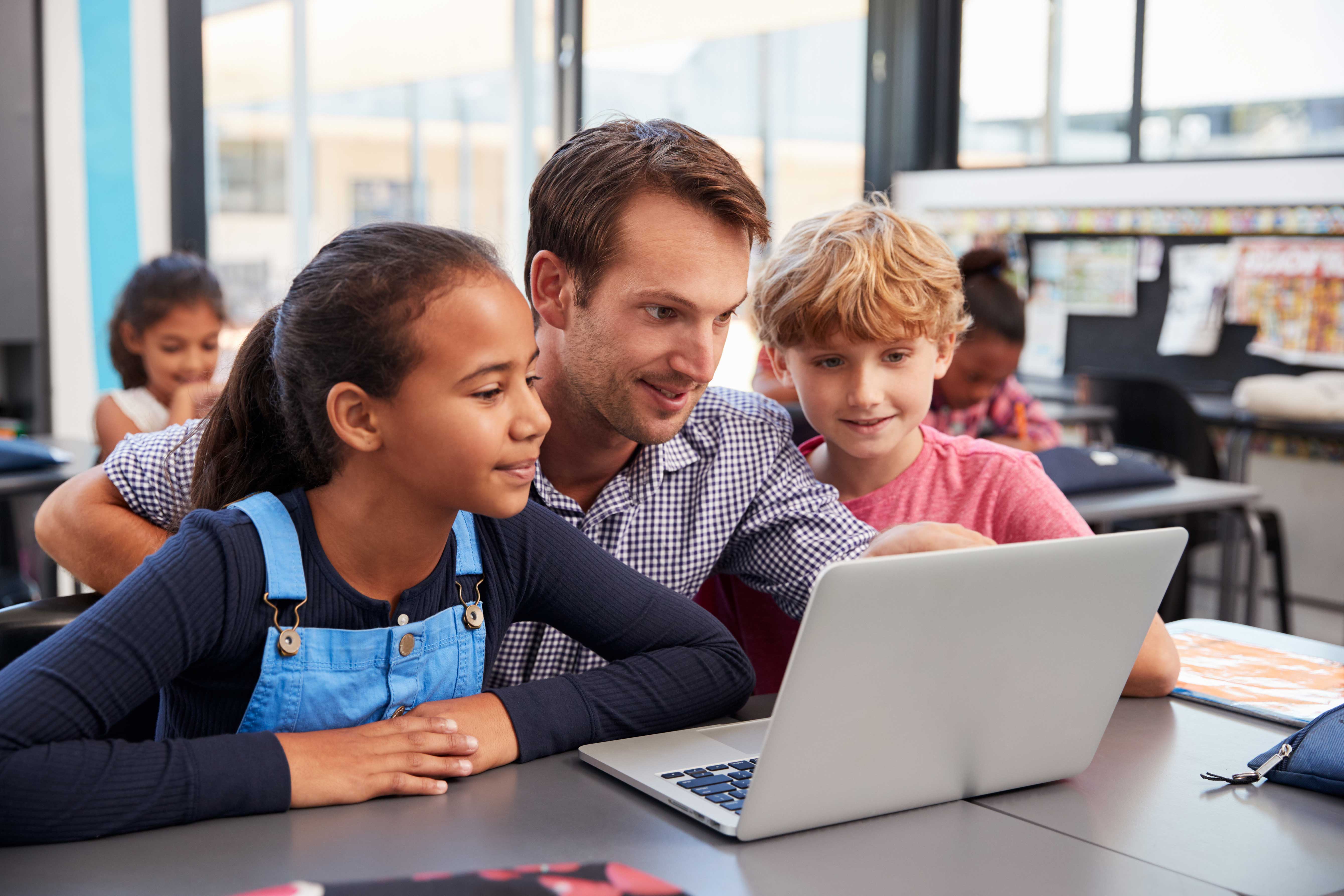 a mentor teaching students on a laptop