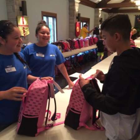 Students help to stuff supplies into backpacks and check them.