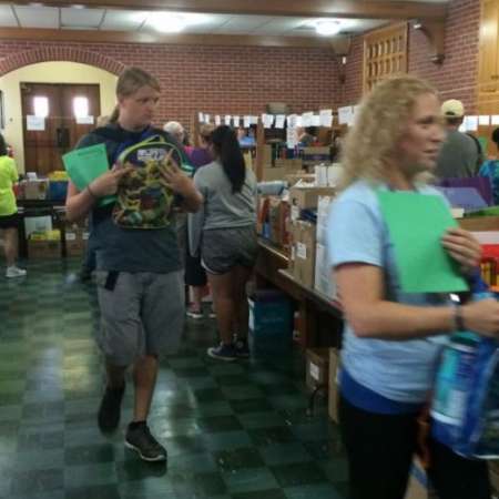 Volunteers fill backpacks with school supplies.