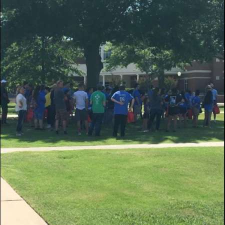 Students group under tree at end of tour.