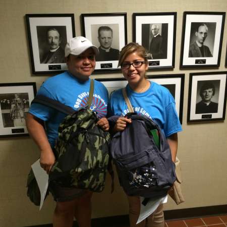 Mariana and her parent help pack backpacks.